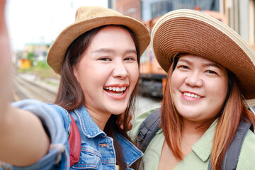 Portrait of two happy Asian women traveling by train. Hold your smartphone and take a selfie. Tourism concept. Traveling by train in Thailand. outdoor adventure travel