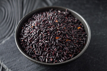 raw fresh black rice on black wooden rustic background