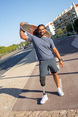 Portrait of energetic bearded man with skateboard. Mid adult sportsman in casual clothes and...