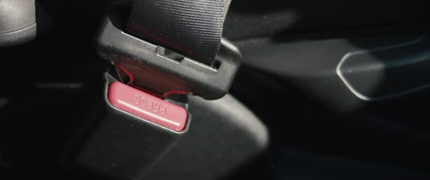 Female hand buckles up releases safety belt woman in car in close up