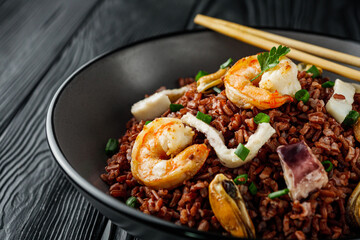 delicious red rice with shrimps and seafood on a black wooden rustic background