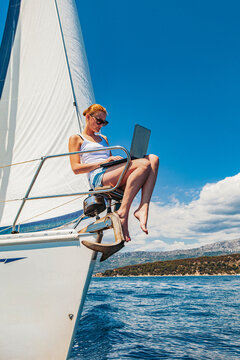 Woman with the laptop on the stem of the sailboat