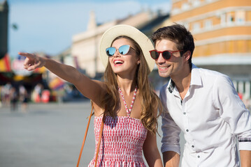 Young couple tourists sightseeing in the city on a sunny summer day 