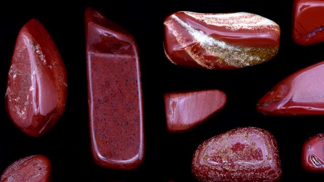 Red jasper rare jewel stones texture on black background. Moving right seamless loop backdrop.