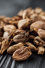 a barrel of dried black cardamom on a black wooden rustic background
