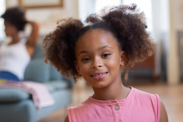 Portrait of cute African American girl in pink overall. Cute child with curly hair looking at camera, posing, smiling. Portrait, childhood concept