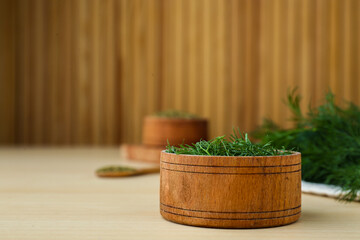 Bowl of fresh dill on wooden table, space for text