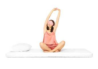 Woman in sleep mask stretching on soft mattress against white background