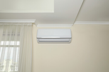 Modern air conditioner on white wall indoors