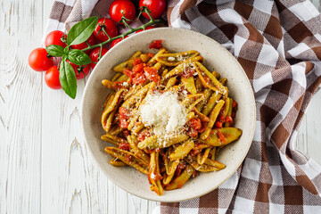 green cavatelli pasta with spinach in tomato sauce on a white wooden background
