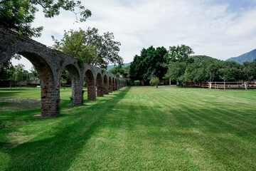Fototapeta na wymiar Arcos de acueducto de hacienda colonial antigua en verano con árboles