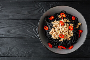 delicious black spaghetti pasta on a black rustic wooden background