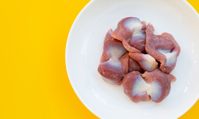 Chicken gizzard in white plate on yellow background.
