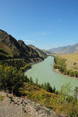 A turn in the bed of a beautiful river flowing through a valley at the foot of a high mountain range.