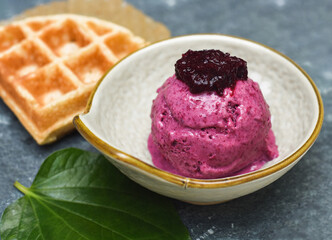 Hibiscus organic ice cream with waffle on stone plate with spoon and fork