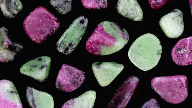 Ruby zoisite rare jewel stones texture on black surface background. Moving right seamless loop backdrop.
