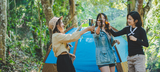 Young woman cheer and drink beverage front of camping tent