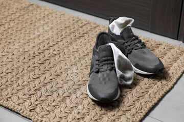 Sneakers with dirty socks on woven mat indoors, closeup. Space for text