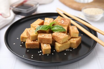 Plate with delicious fried tofu, basil and sesame seeds on white table, closeup