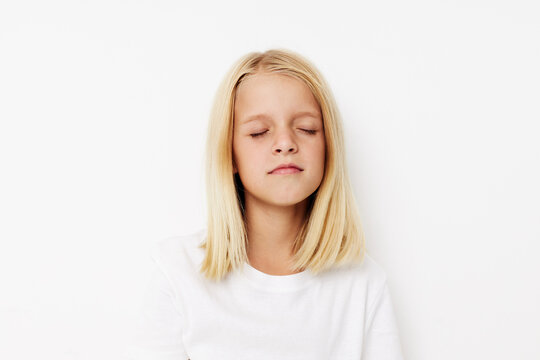 Beautiful little girl in a white t-shirt grimace on a light background
