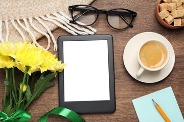 Flat lay composition with e-book reader, cup of coffee and flowers on wooden table. Space for text