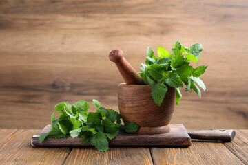 Mortar with pestle and fresh lemon balm on wooden table