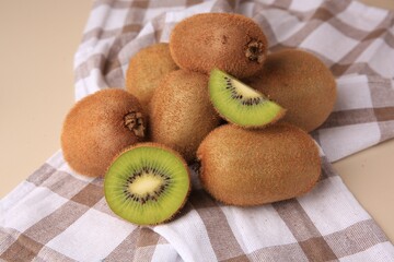 Heap of whole and cut fresh kiwis on beige table