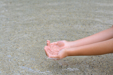 Fototapeta na wymiar Kid dipping hands in water outdoors, closeup. Space for text