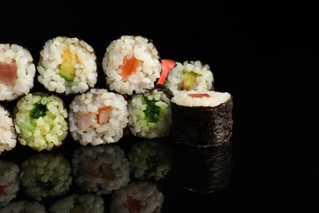 Set of delicious sushi rolls on black background, closeup