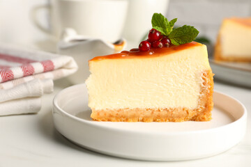 Piece of delicious caramel cheesecake with red currants and mint served on white marble table, closeup