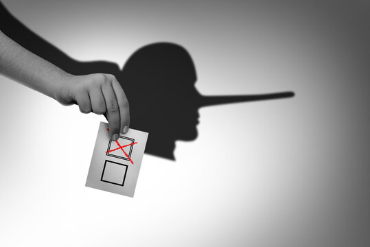 Vote fraud and Election dishonest voting or rigging elections and voter deception crime as a hand with a ballot casting a shadow of a liar or Lieing as an illegal electoral activity 