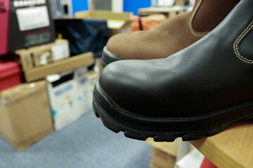 Photo of brown and black leather safety shoes on the warehouse table