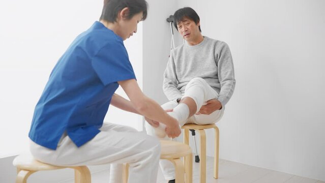 医者に包帯を巻かれる中年男性　医療イメージ