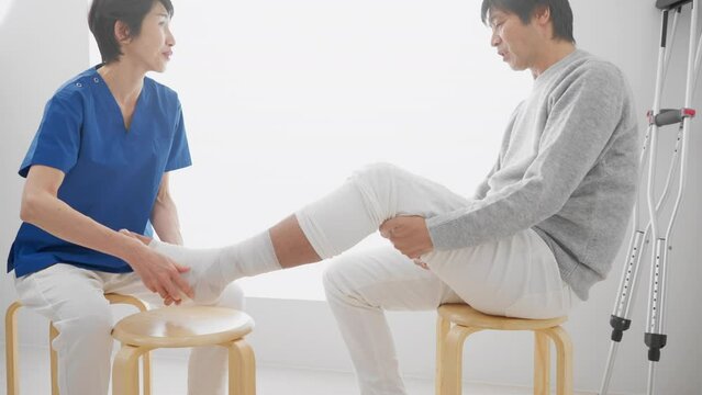 医者に包帯を巻かれる中年男性　医療イメージ