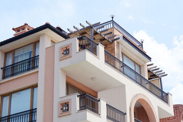 Exterior of residential building with balconies against blue sky, low angle view