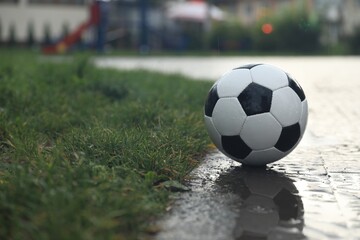 Fototapeta na wymiar Wet leather soccer ball on street, space for text