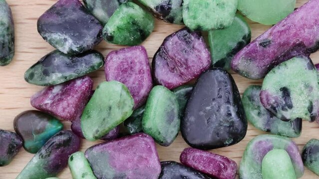 Ruby zoisite jewel stones heap up texture on light varnished wood background. Moving right seamless loop backdrop.