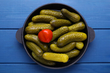 Serving pan with pickled cucumbers and pepper on blue wooden table, top view