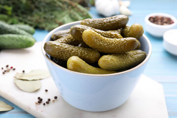 Bowl with pickled cucumbers on light blue table, closeup