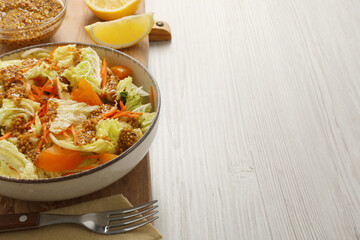 Delicious salad with Chinese cabbage and mustard seed dressing on white wooden table. Space for text