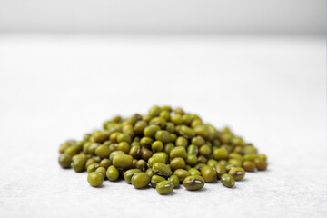 Pile of green mung beans on light grey table, closeup