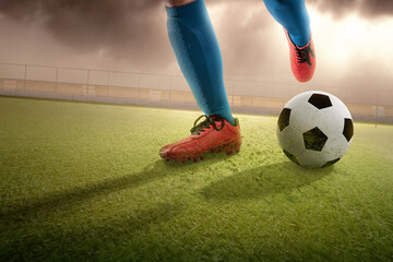 Football player man in a blue jersey kicking the ball