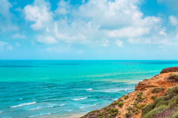 Fototapeta na wymiar Seascape with azure sea, yellow rock and blue sky