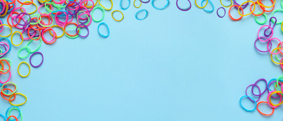 Many colorful rubber bands on light blue background with space for text