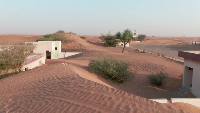Drone flight over sand-covered Arab houses in the desert