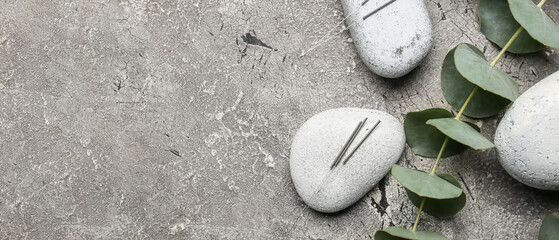 Acupuncture needles, eucalyptus branches and spa stones on grey background space for text, top view