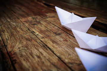 Origami, white paper boat isolated on a wooden floor. Paper boats mean walking. feeling of freedom leadership