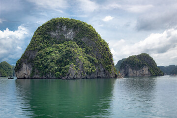 Fototapeta na wymiar Tropical island limestone mountains, water, and boat view along the ocean sea at Halong Bay in Vietnam