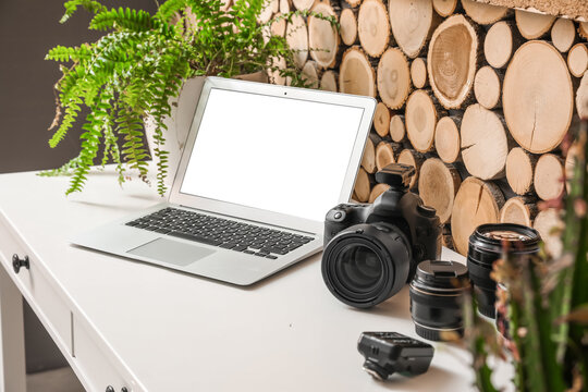 Photographer's workplace with laptop and equipment near wooden wall