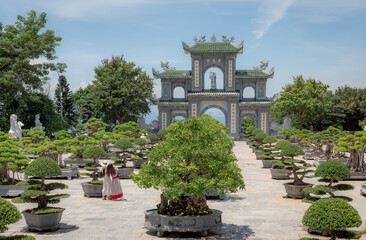 Fototapeta na wymiar Traditional stone arch gate structure, garden, and tropical forest coastline in Chùa Linh Ứng Buddhist temple in DaNang Vietnam 